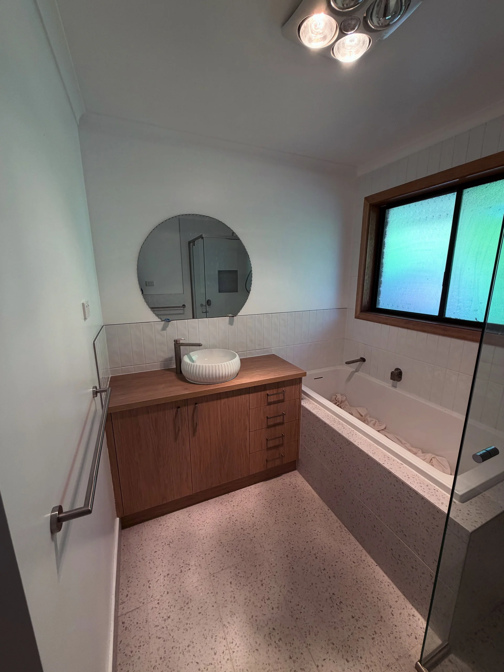 Completed C & C Build Co bathroom with a timber vanity, fluted basin and terrazzo bath surround