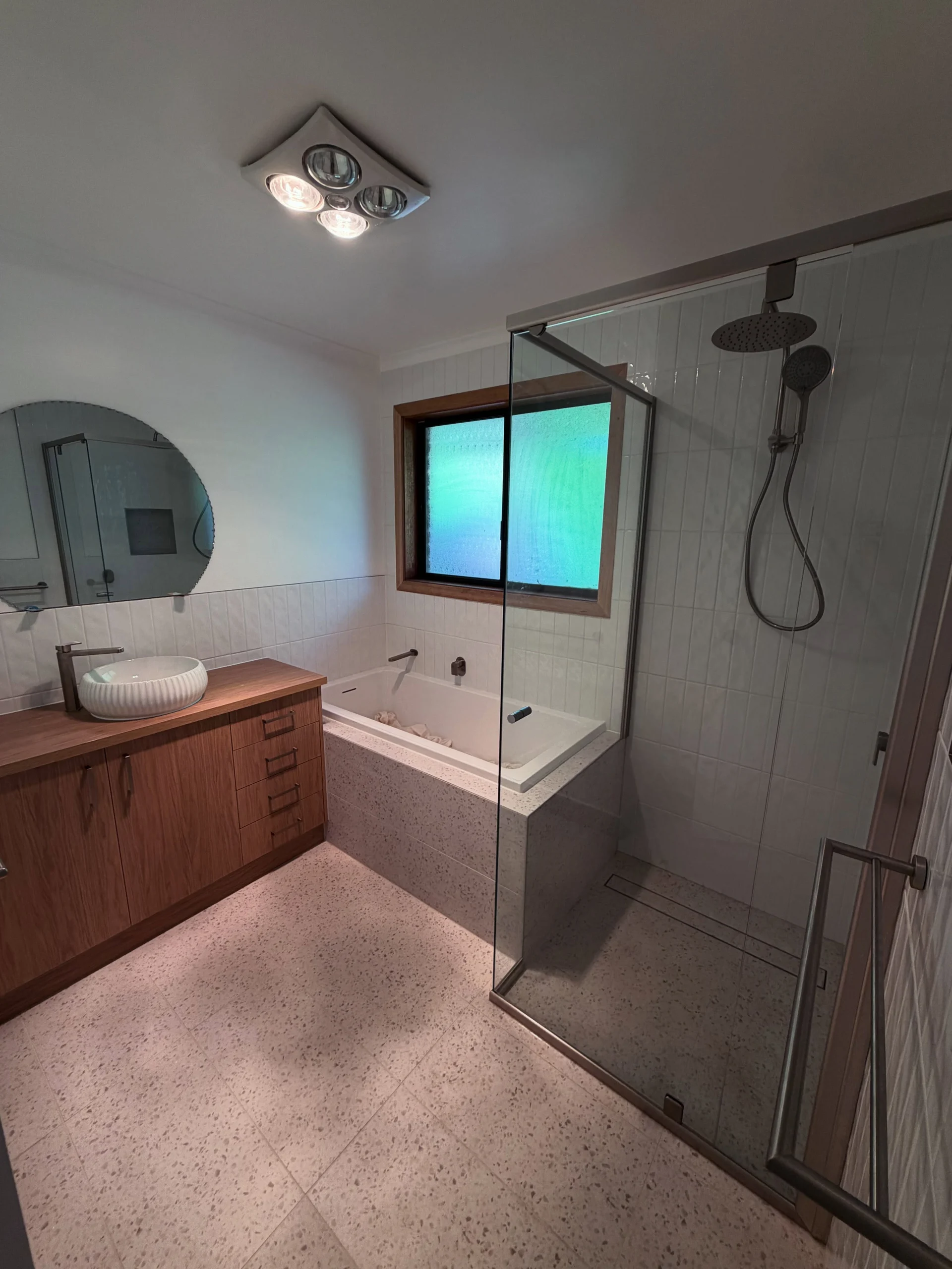 Timber vanity, terrazzo floor and glass shower in a completed bathroom renovation