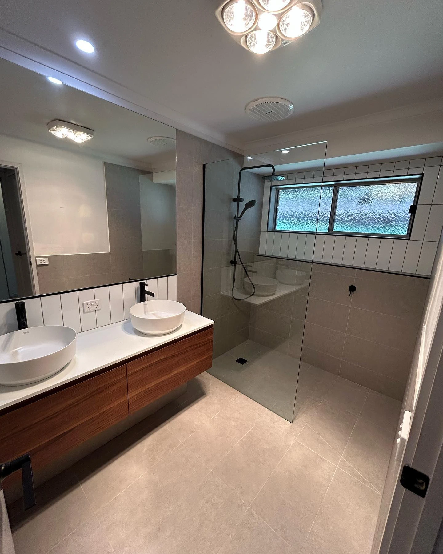 C & C Build Co’s completed Mooroopna bathroom with a timber double vanity, white basins and a glass shower